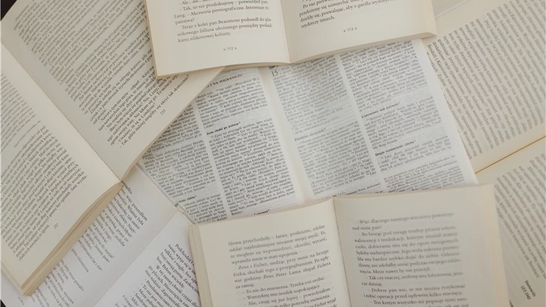 From above of opened books with white pages placed above each other in library