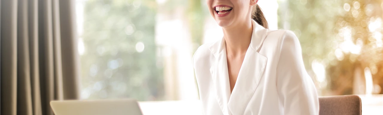 Laughing businesswoman working in office with laptop