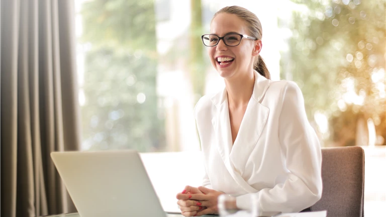 Laughing businesswoman working in office with laptop