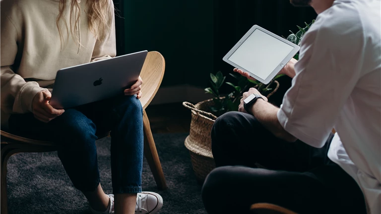 Photo of Couple Talking While Holding Laptop and Ipad