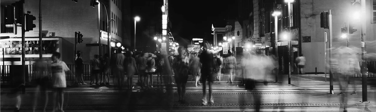 Group of People Crossing Pedestrian Lane in Greyscale