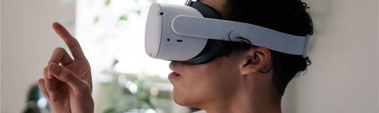 Side view of concentrated young guy in casual clothes experiencing virtual reality in modern headset at home